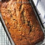 An overhead shot of banana bread cooling off in the pan on a cooling rack.