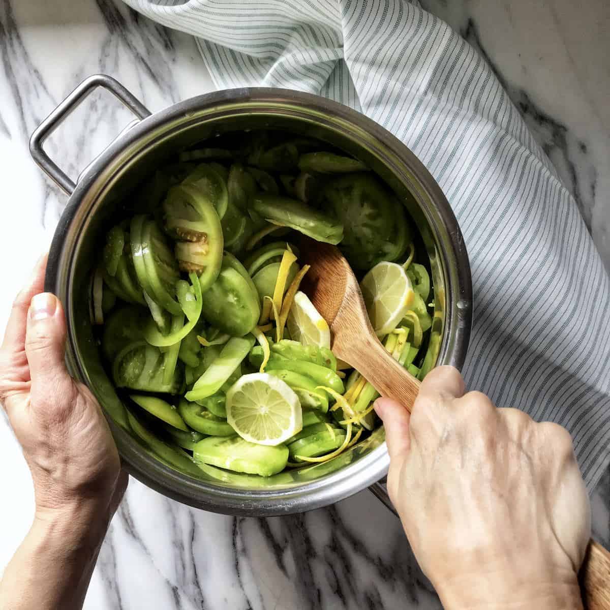 Sliced green tomatoes being mixed together in a pot.