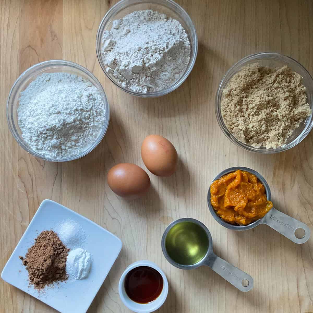 Ingredients to make pumpkin spice biscotti on a wooden board.