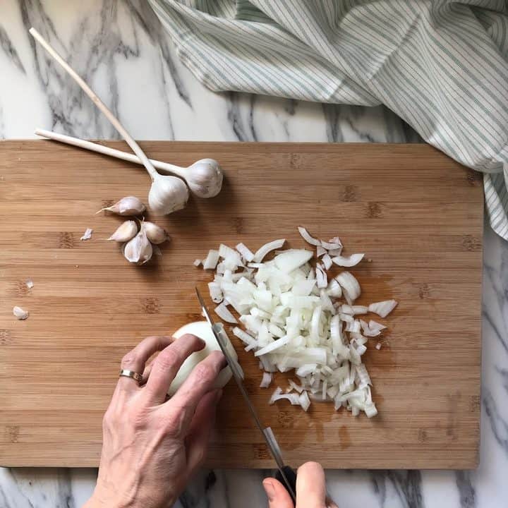 Chopped onions on a wooden cutting board.