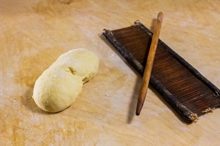 A ball of dough and an original board and rod, called "petene" and "fuso" to make caragnoli. 