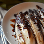 Grilled radicchio with a balsamic drizzle on a white oval plate.