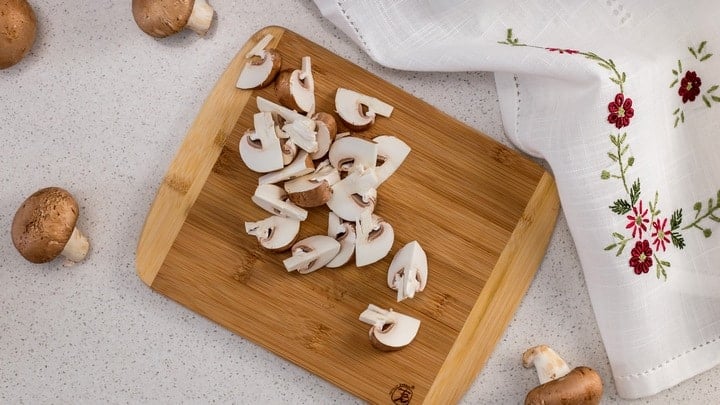 An overhead shot of sliced mushrooms as they are prepped to get oven roasted.