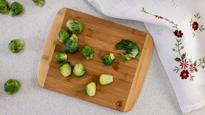 An overhead shot of halved Brussels sprouts on a wooden cutting board. They are one of the best oven roasted vegetables.