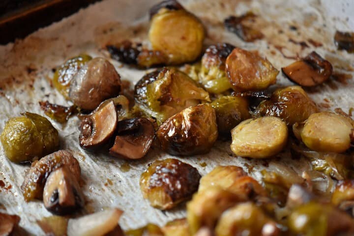 A close up shot of caramelized Brussel sprouts on a parchment lined baking sheet.