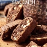 A pile of chocolate biscotti on a wooden board.