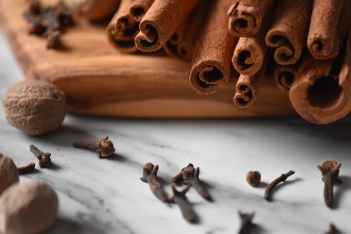 A close up of cloves, whole nutmeg and cinnamon sticks; 3 ingredients to make this allspice recipe.