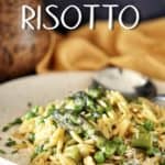 Orzo risotto on a plate garnished with fresh Italian parsley and grated cheese.