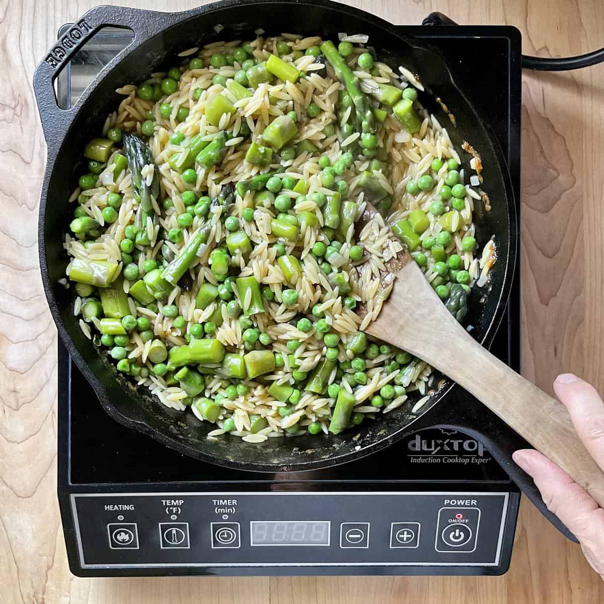 An overhead shot of the combination of peas and asparagus to orzo pasta.