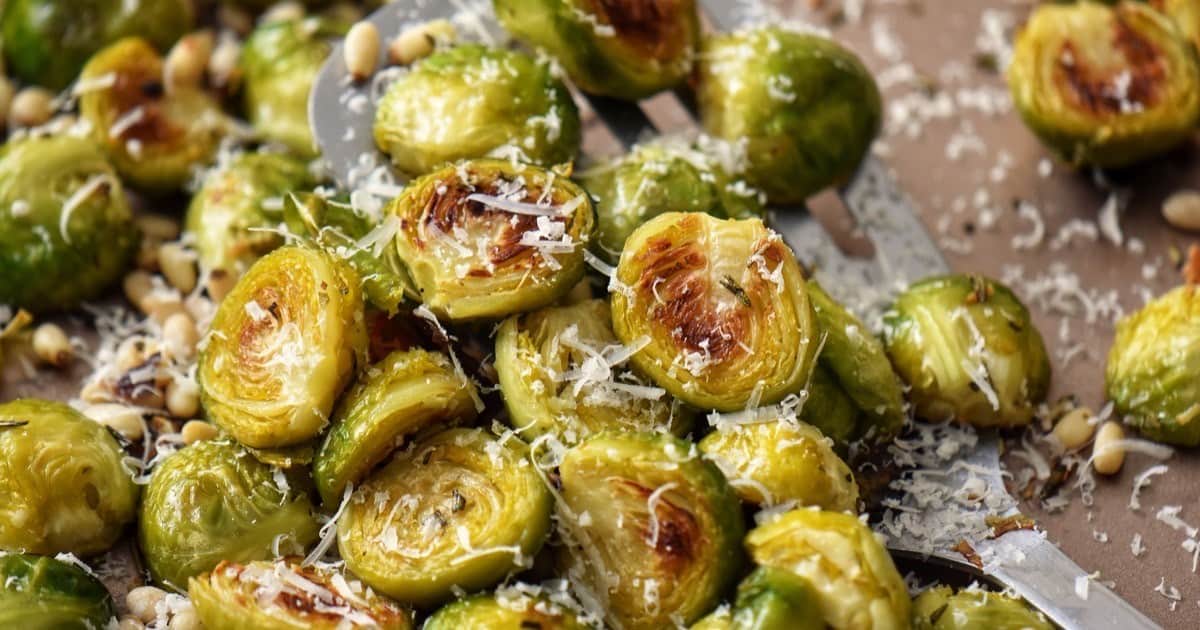 Roasted Brussels sprouts on a platter, with grated Parmesan cheese grated over the top.