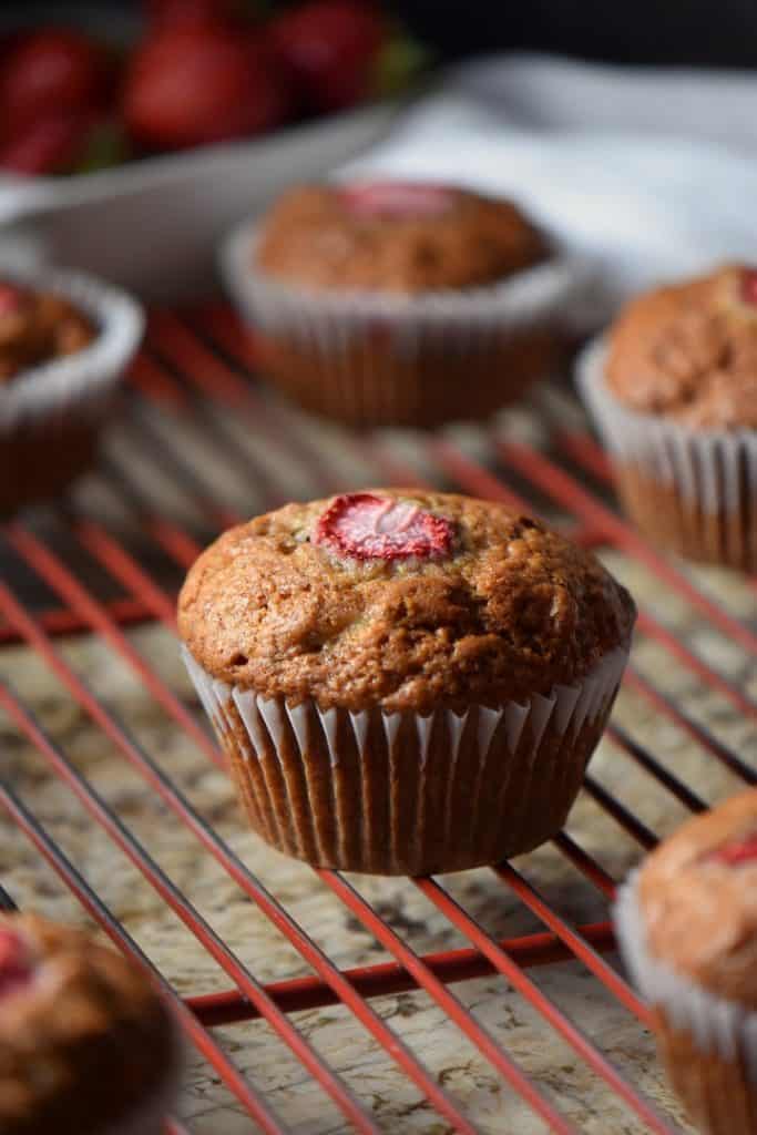 A banana strawberry muffin placed on a red cooling rack.