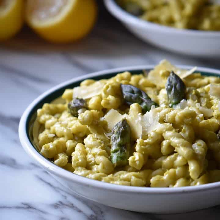 A bowl of gemelli pasta with a few asparagus tips.