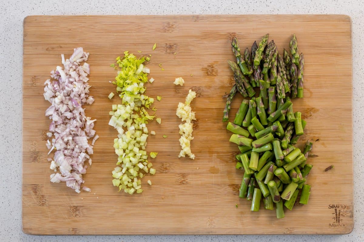 Chopped shallots, celery , garlic and asparagus on a wooden board.