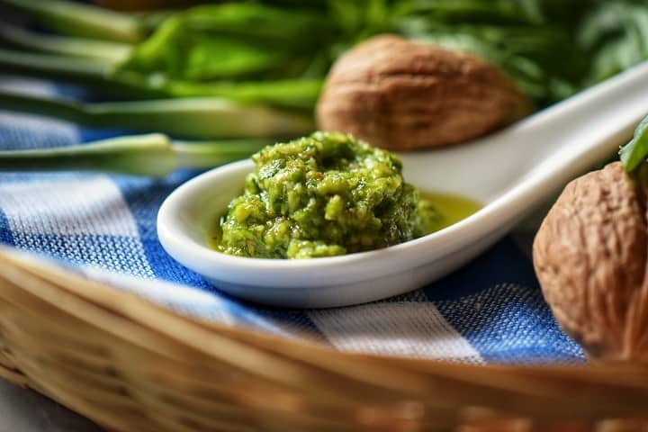 A closeup shot of freshly made garlic scape placed on a white ceramic spoon.