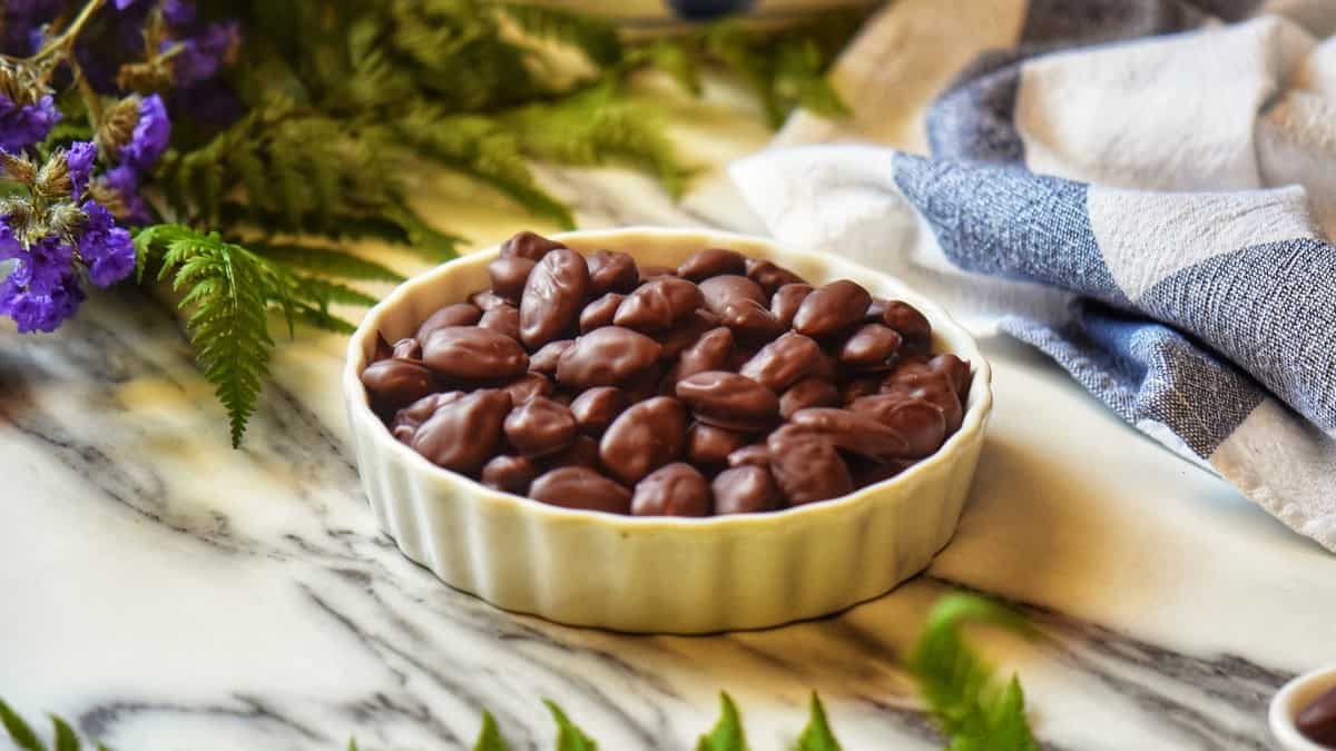 Chocolate covered nuts in a white ceramic bowl, surrounded by a tea tower.