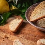 A sliced lemon biscotti next to whole lemons.