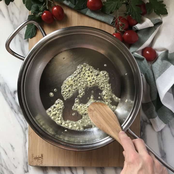 Olive oil and chopped garlic being heated in a large pan.