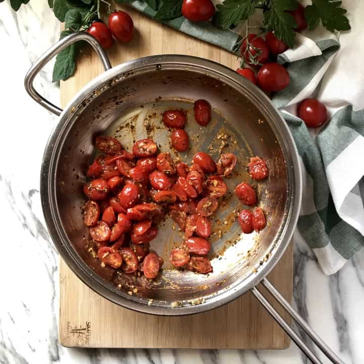 A cherry tomato topping in a large saucepan for a pesto pizza.