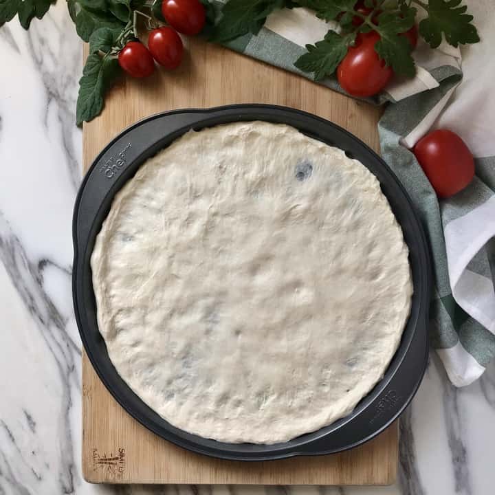 Pizza dough stretched out in a pan.