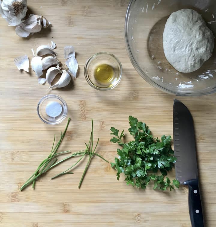 Fresh Italian parsley next to garlic cloves, about to be chopped.