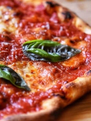 Basil leaves garnish a freshly grilled Italian pizza.