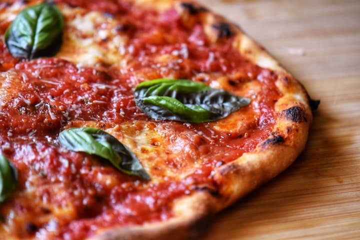 An overhead shot of margherita pizza topped with basil leaves. 