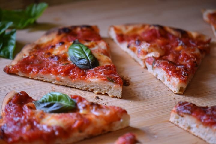 Slices of margherita Pizza on a wooden board.