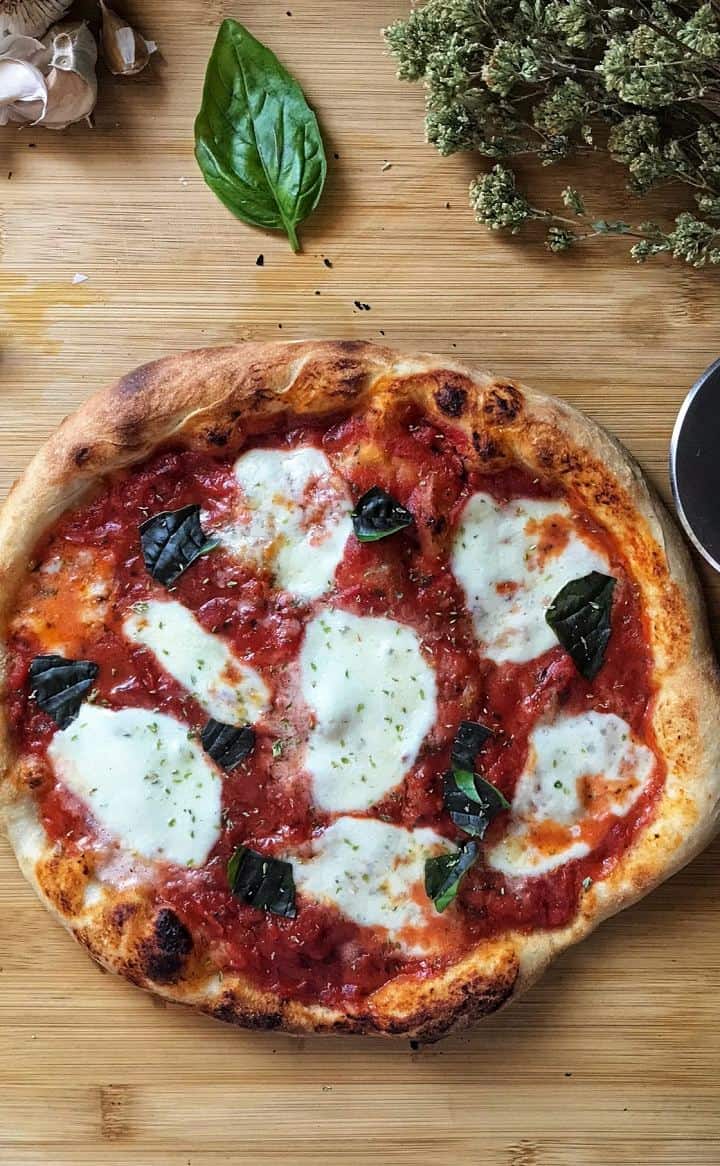 An overhead shot of margherita pizza topped with basil leaves. 