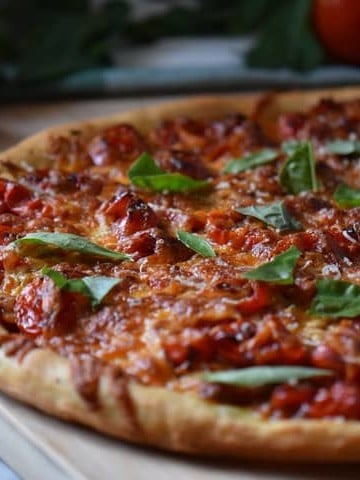 A freshly made pizza with cherry tomatoes and pesto, fresh out of the oven.