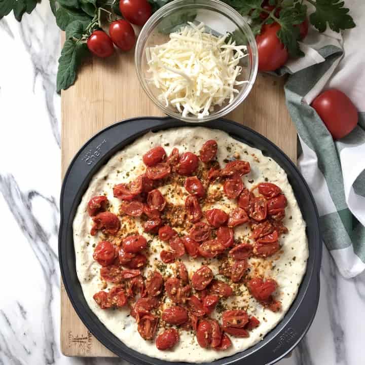 Sauteed cherry tomatoes being spread over the basil pesto.