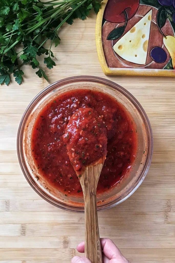 A large wooden spoon of freshly made homemade canned pizza sauce.