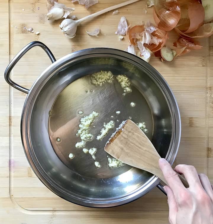 Chopped garlic being sauteed in a large pan.