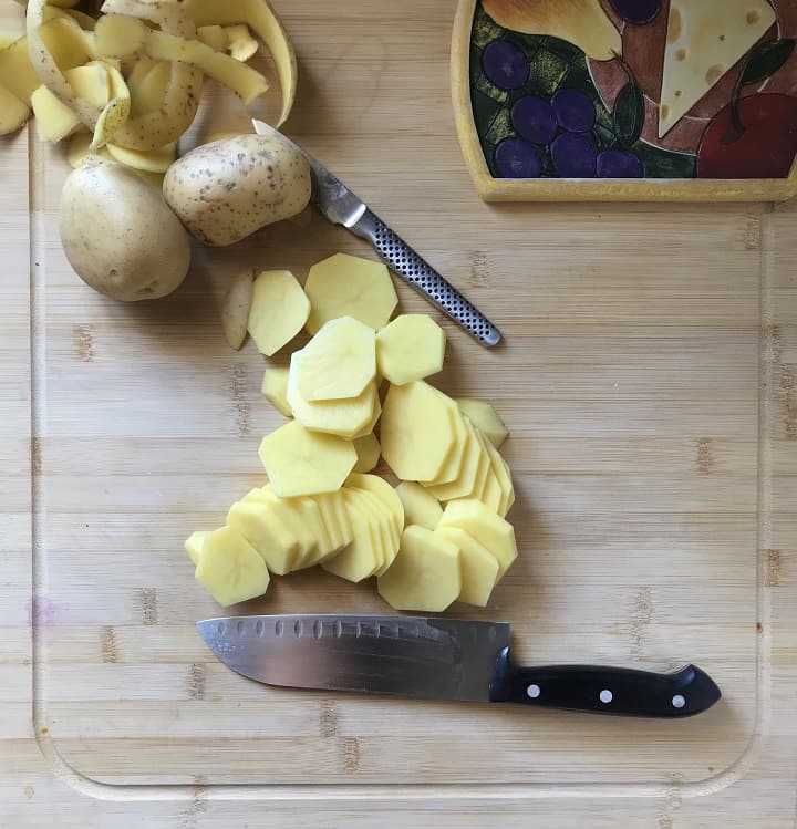 Sliced potatoes on a wooden board.