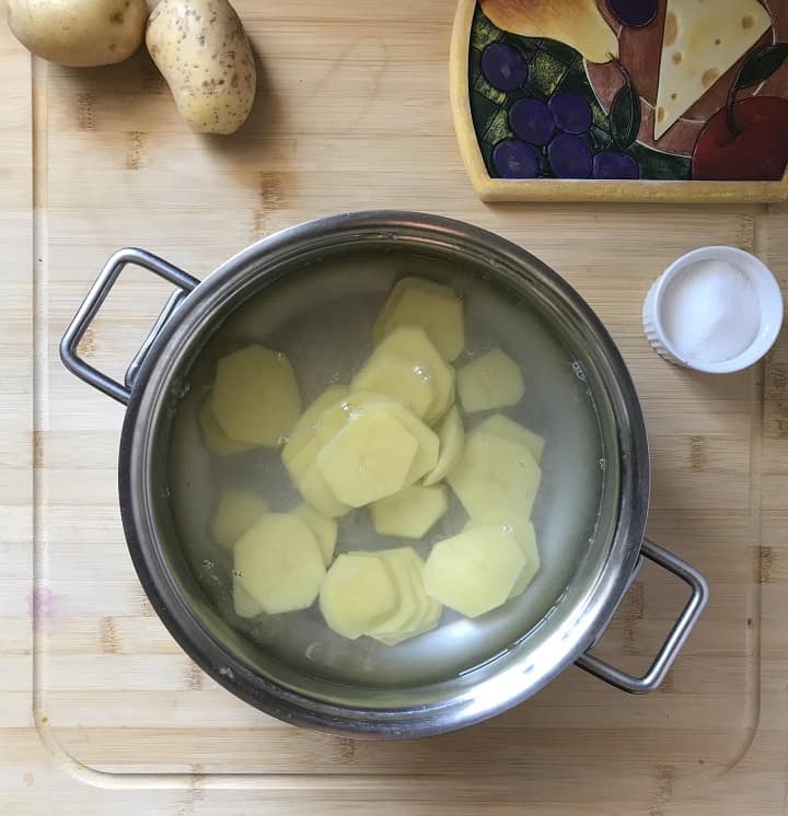 Sliced potatoes in a large pot of salted water.