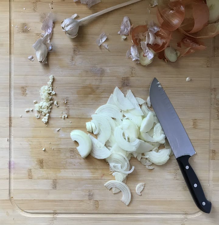 Sliced onions and chopped garlic on a wooden board.