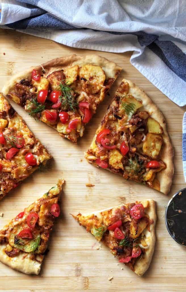 Chopped fresh tomatoes and dill added as a garnish to an Italian pizza.