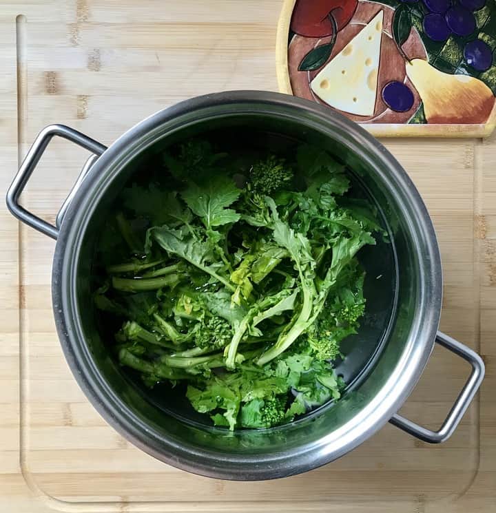 Broccoli rabe in a large pot of salted water, about to be parboiled.