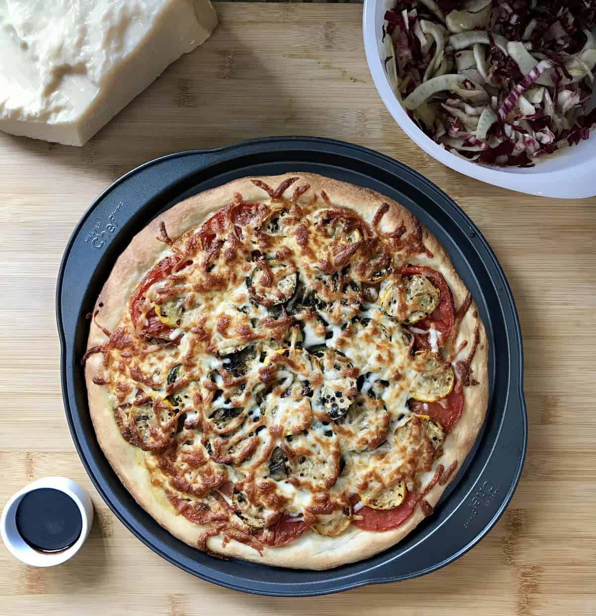 A fresh from the oven vegetarian pizza next to a bowl of endive, radicchio and fennel salad.