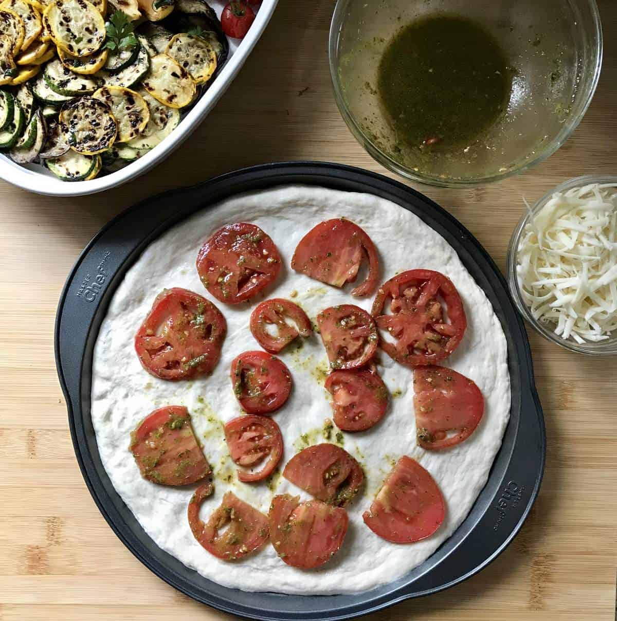 Marinated tomatoes (in basil pesto) on pizza dough creates the base of the salad pizza.