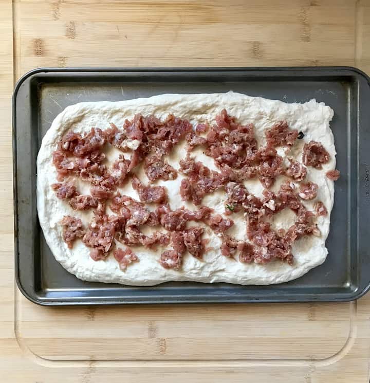 Loose Italian sausage spread over the stretched out pizza dough.