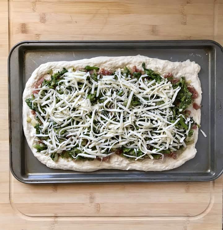 Broccoli rabe and mozzarella spread over pizza dough to make sausage pinwheels.