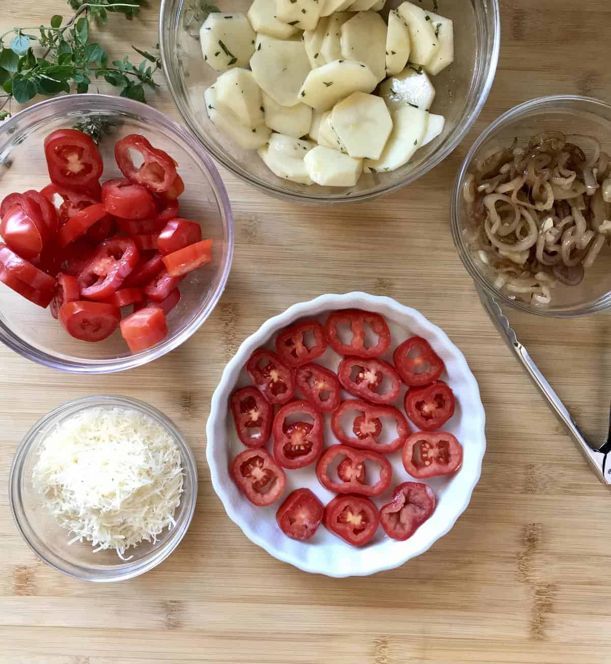 Layers of thinly sliced Roma tomatoes at the bottom of a baking dish.