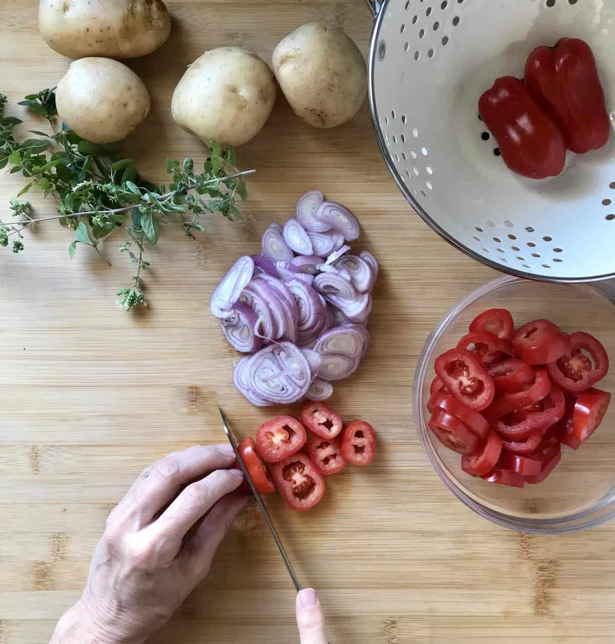 Sliced shallots and tomatoes on a wooden board.