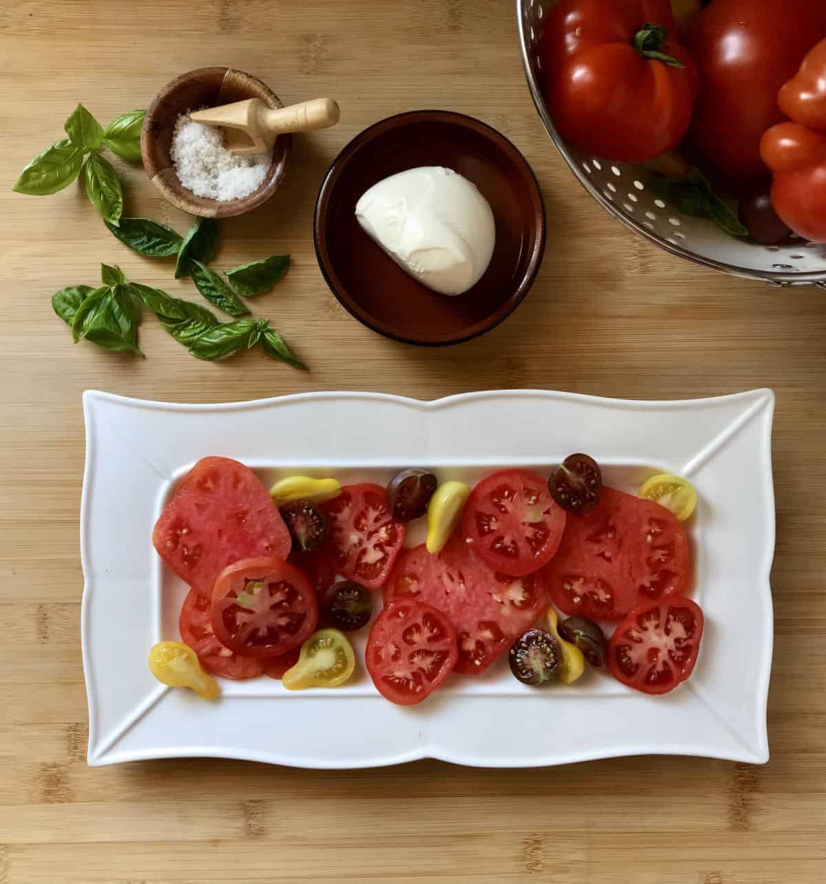A variety of sliced heirloom tomatoes placed in a white serving dish.