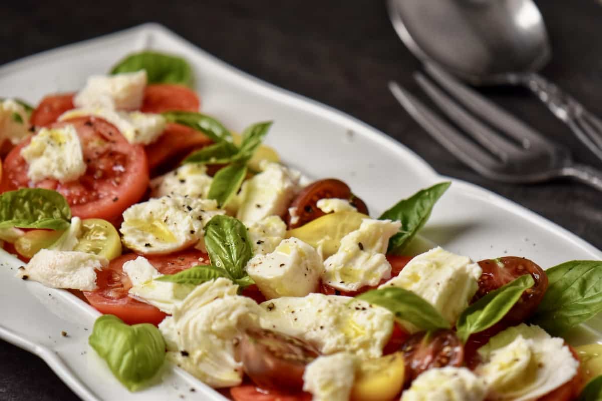 Mozzarella cheese on slices of tomato. surrounded by basil leaves.