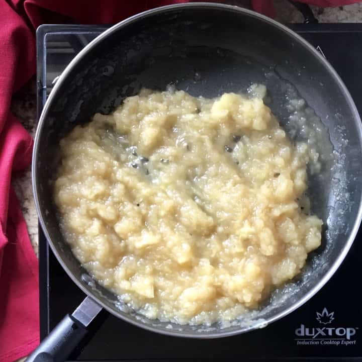 Cooked apples with the consistency of chunky applesauce in a saucepan.