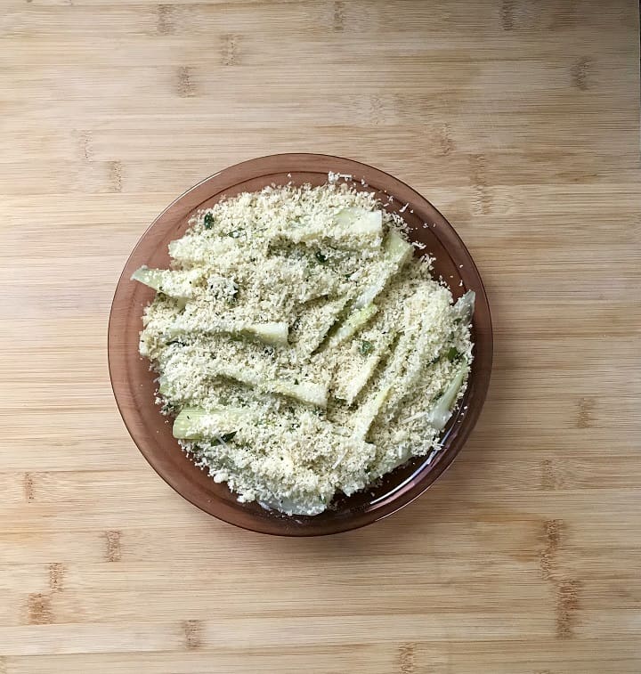 Sliced fennel topped with a mixture of panko bread crumbs and herbs in a round dish, ready to be oven baked.