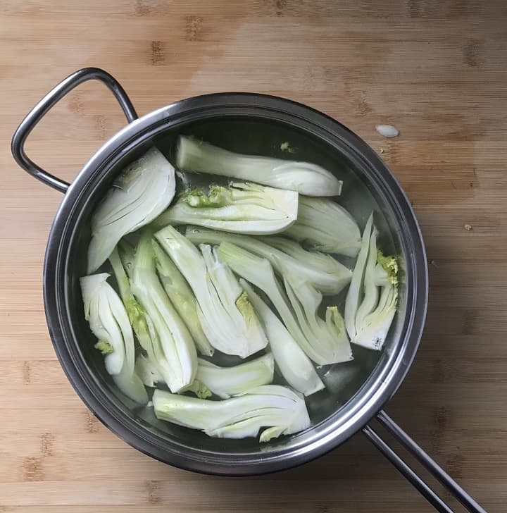 Sliced fennel simmering in a large pan of salt water.