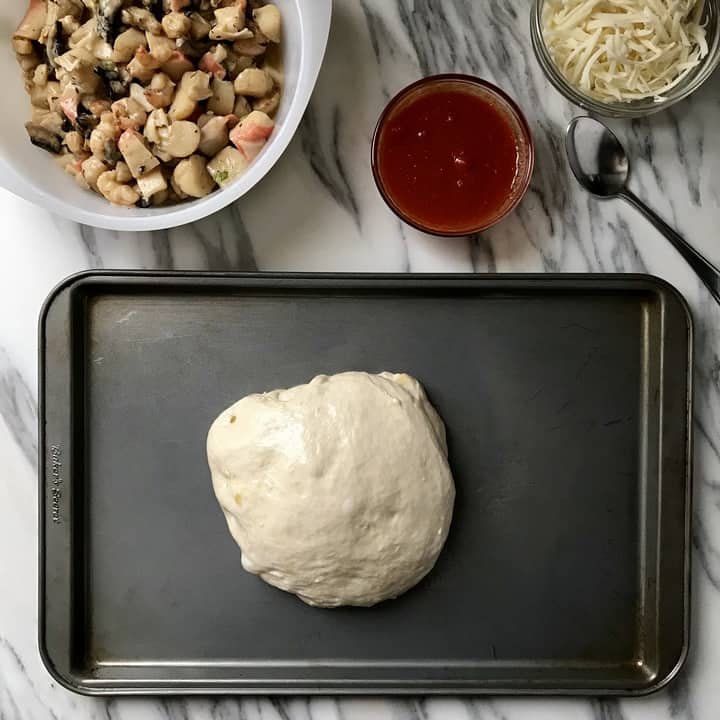 A ball of pizza dough placed in a rectangular pizza pan forms the base of our seafood pizza.