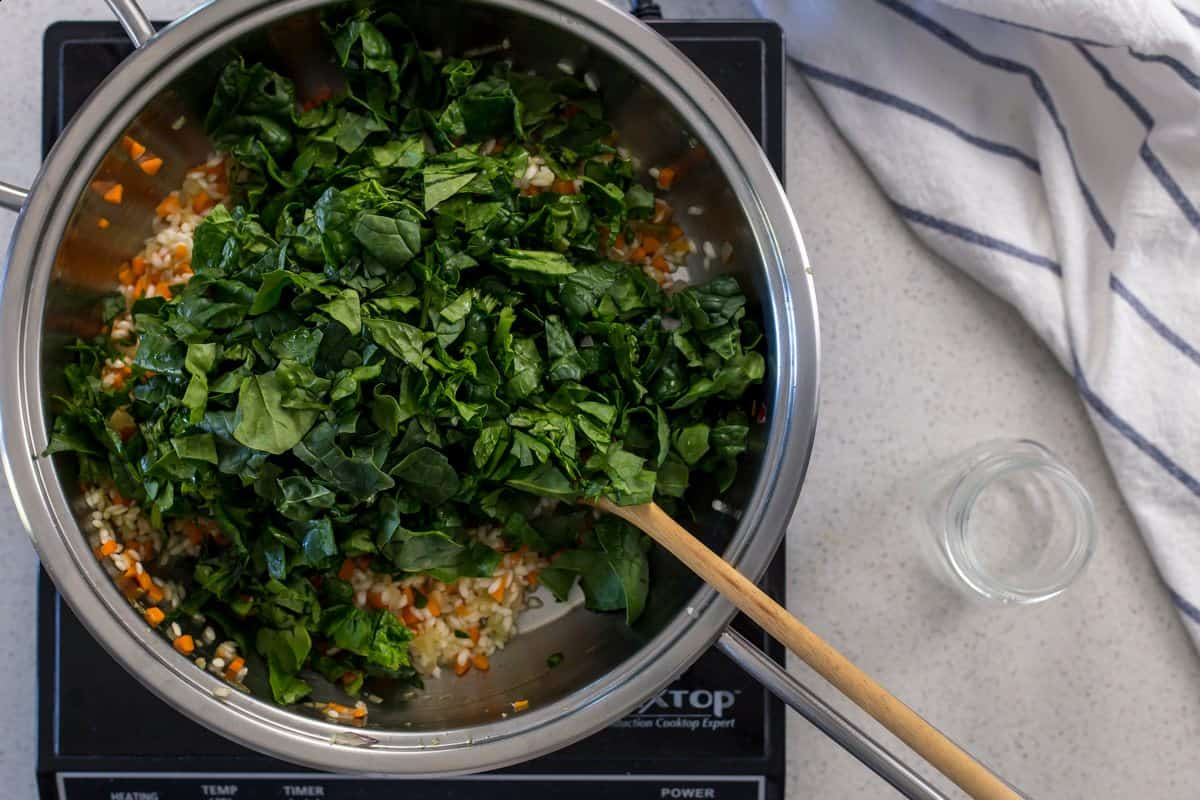 Spinach is added to the rest of the ingredients in a saucepan.